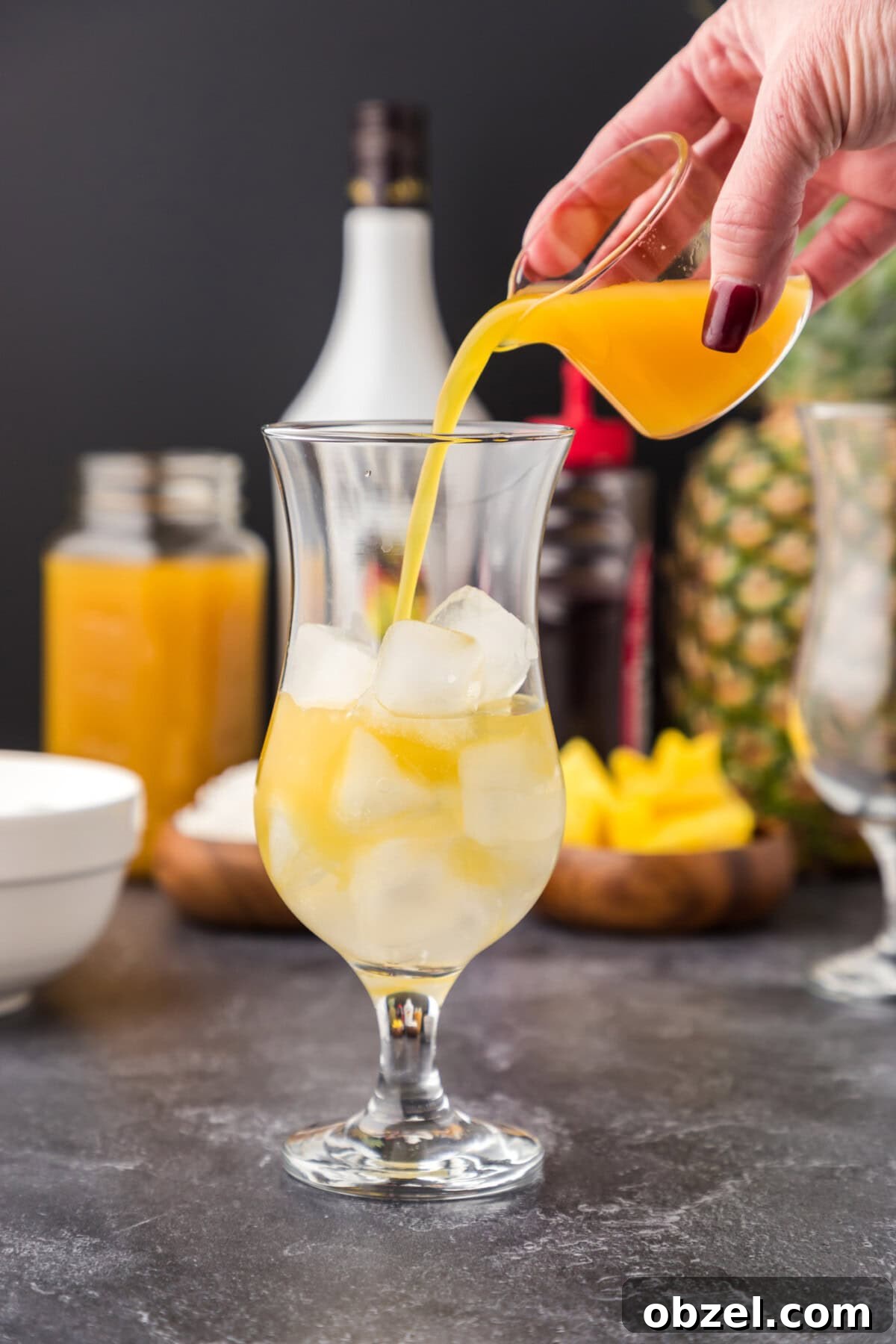 Malibu Sunset: Where to Watch, Photograph and Enjoy 7 pouring pineapple juice into glass of Malibu rum and ice