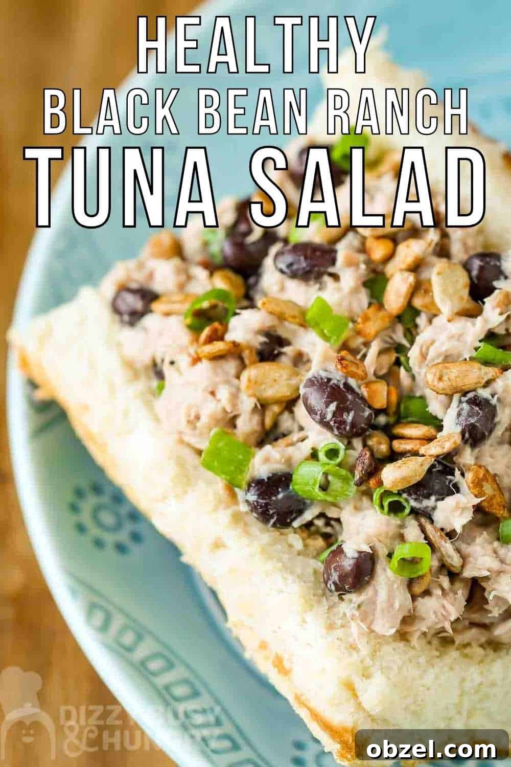Close up view of tuna salad sandwich garnished with herbs on a light blue plate.