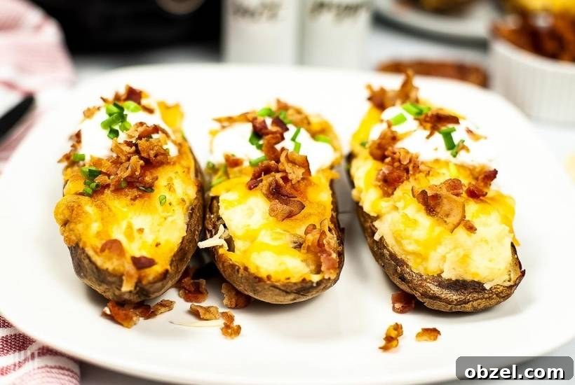 Cheesy Air Fryer Twice-Baked Potatoes 5 three twice baked potatoes topped with bacon and chives on a white plate