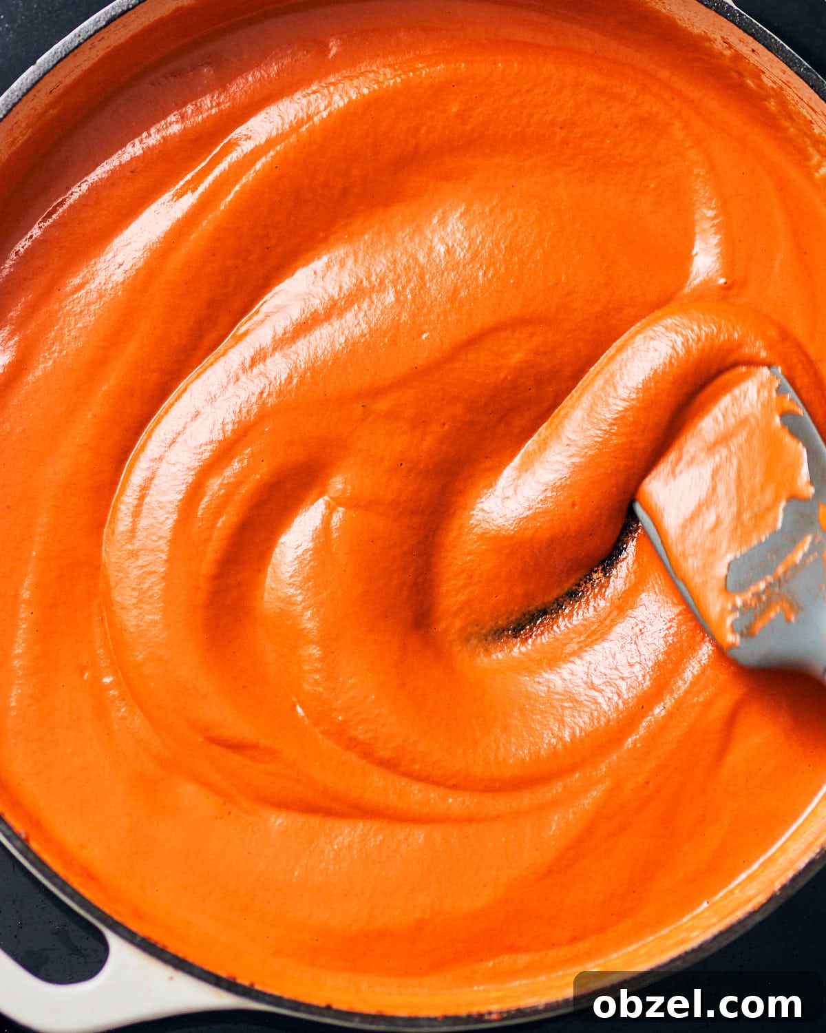 Creamy Vegan Vodka Sauce Pasta 12 Creamy vegan vodka sauce in a pan, being stirred with a spoon