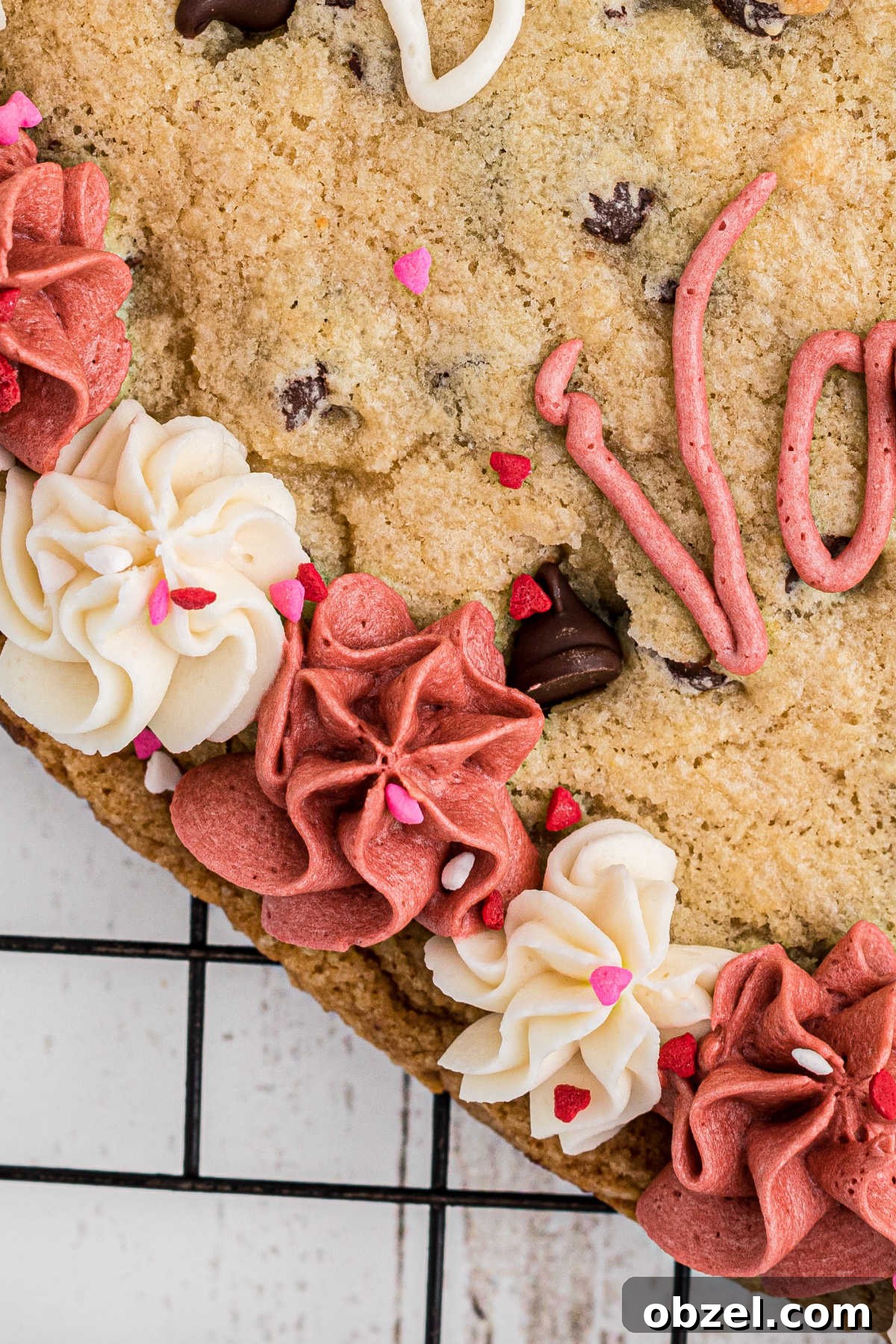 Close up of a side of a giant valentines cookie, of the white and pink frosting.