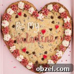 A giant valentines cookie on a pink baking sheet.