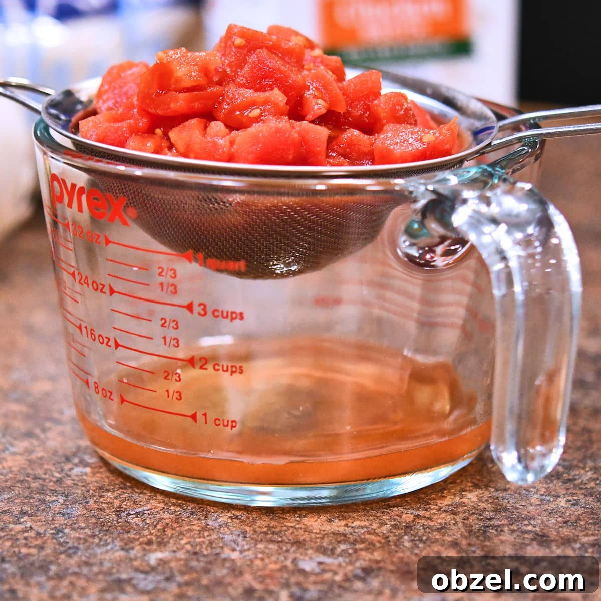 Homemade Mexican Red Rice Recipe 4 Diced tomatoes being strained over a glass measuring cup.